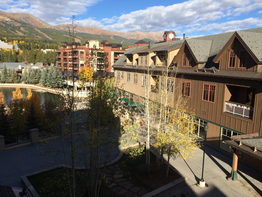 Elevated view of Hyatt Main Street Station in Breckenridge showing the resort's exterior, a scenic pond, and beautiful mountain landscapes.