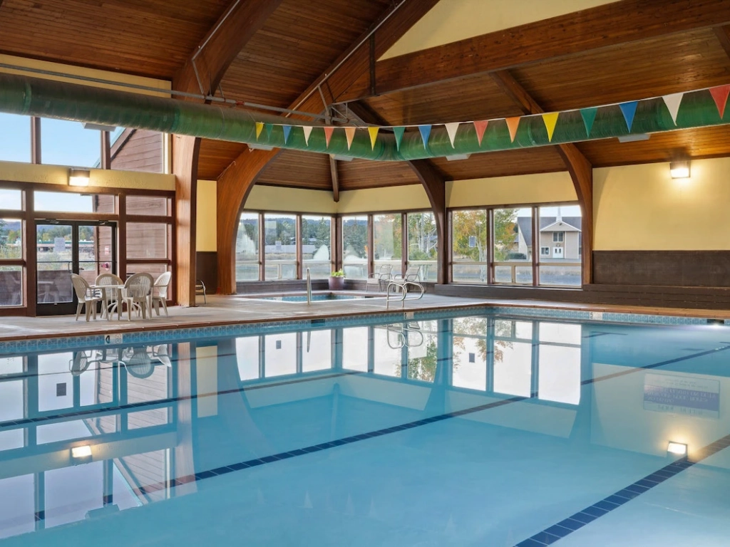 Large indoor swimming pool and relaxing hot tub surrounded by large windows, ideal for unwinding during summer getaways in Colorado.