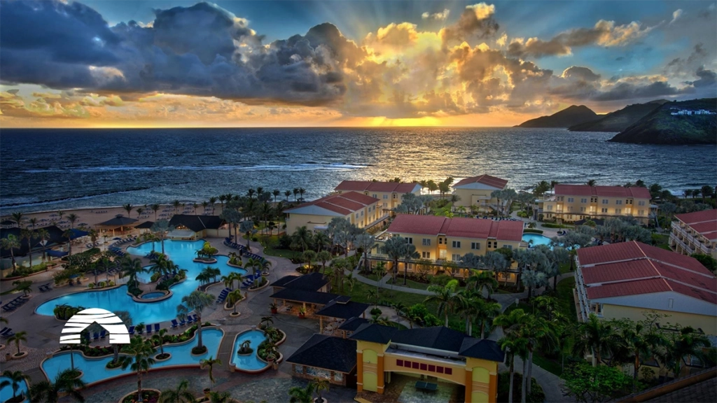 Aerial view of a seaside resort at sunset, with pools, palm trees, and ocean waves. Marriott Timeshare Costs Feature