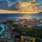 Aerial view of a seaside resort at sunset, with pools, palm trees, and ocean waves. Marriott Timeshare Costs Feature