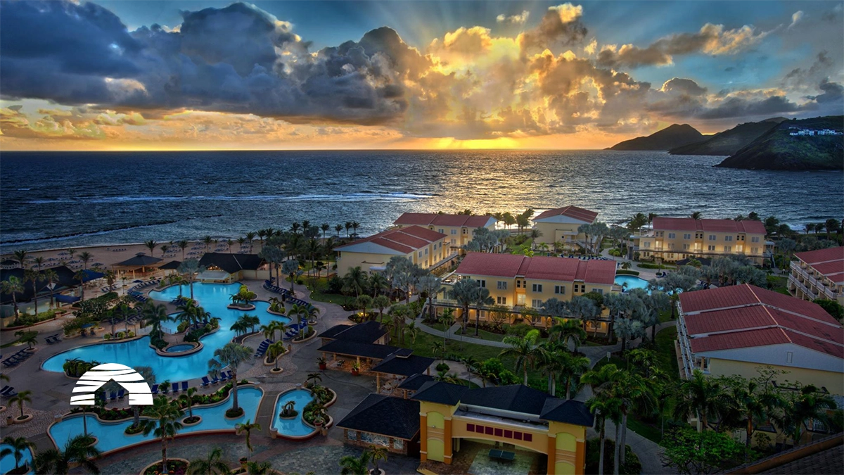 Aerial view of a seaside resort at sunset, with pools, palm trees, and ocean waves. Marriott Timeshare Costs Feature