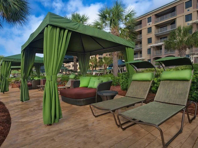 Two lounge chairs and a green cabana with pillows by a poolside area at Marriott Barony Beach Club