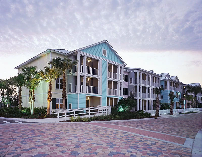 Marriott Timeshare Costs Image: Colorful exterior of Marriott Harbour Lake with palm trees and a brick pathway under a cloudy sky.