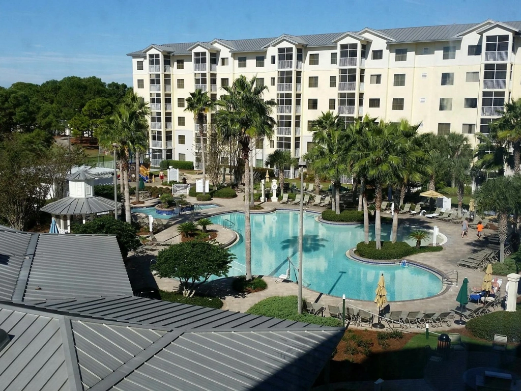 Marriott Timeshare Costs Image: A sunny view of a pool area surrounded by palm trees and Marriott's Legends Edge Baypoint