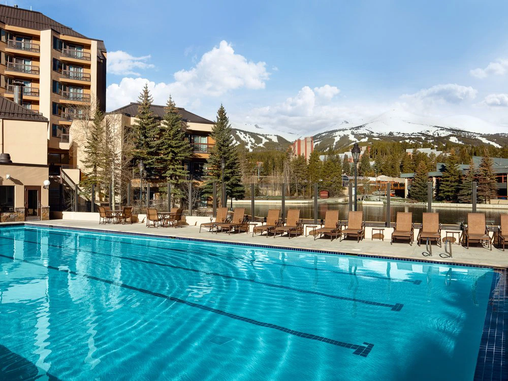 Large outdoor swimming pool at Marriott's Mountain Valley Lodge with lounge chairs and snowy mountains behind.