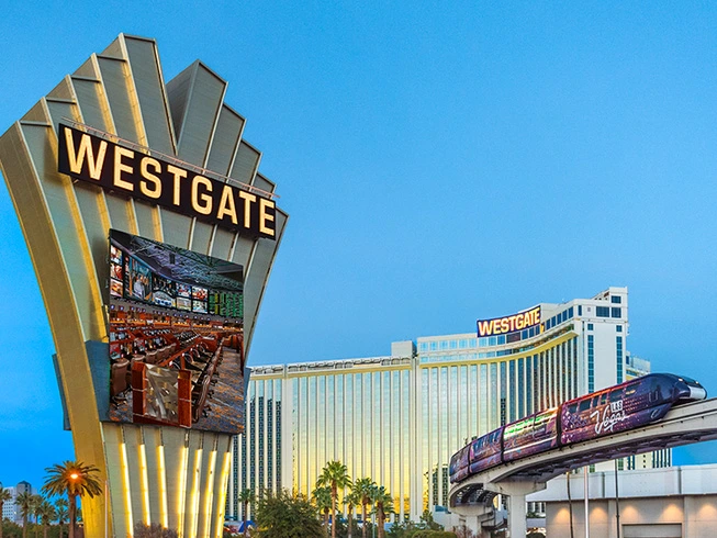 Exterior of Westgate Las Vegas Resort & Casino featuring its large marquee sign and a passing monorail train.
