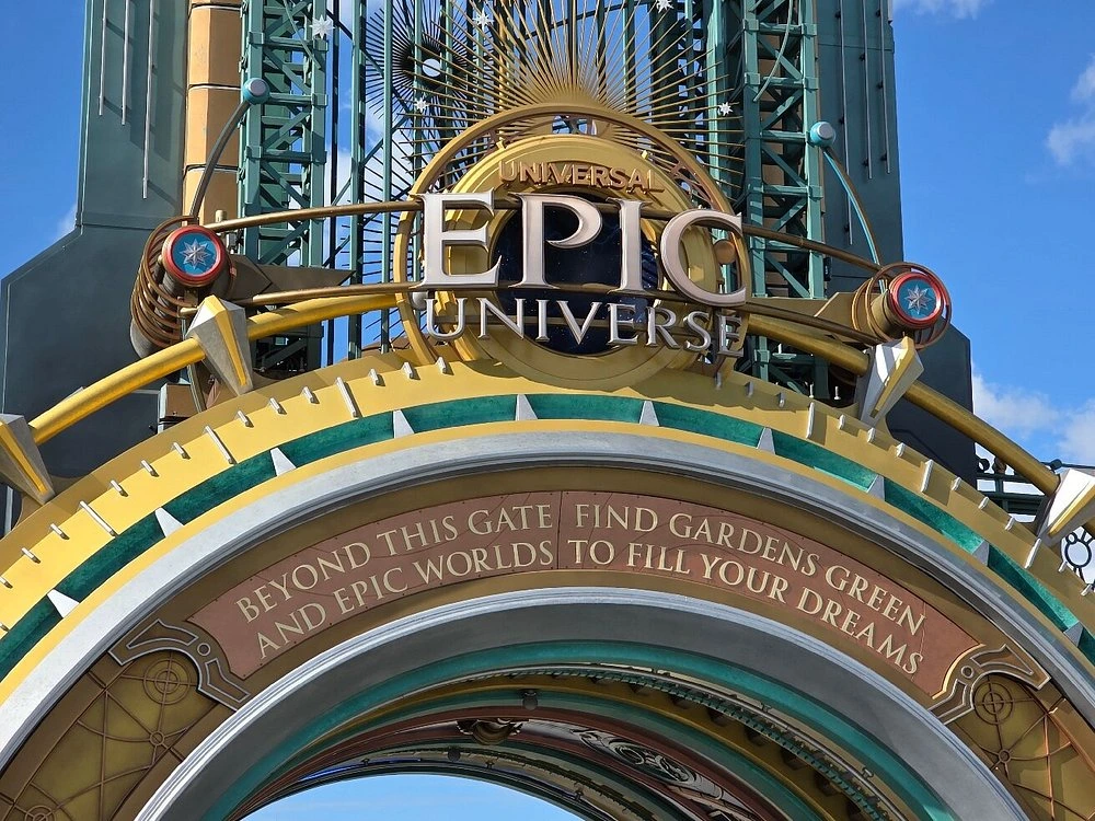 Ornate gold and teal archway featuring celestial designs and an inscribed welcoming quote.