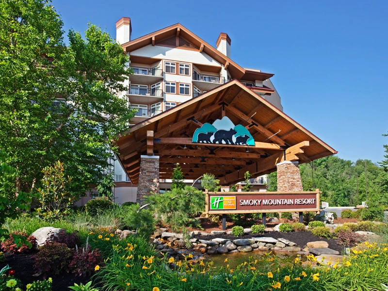 Exterior of the Holiday Inn Smoky Mountain Resort featuring a welcoming wooden entrance and water garden.