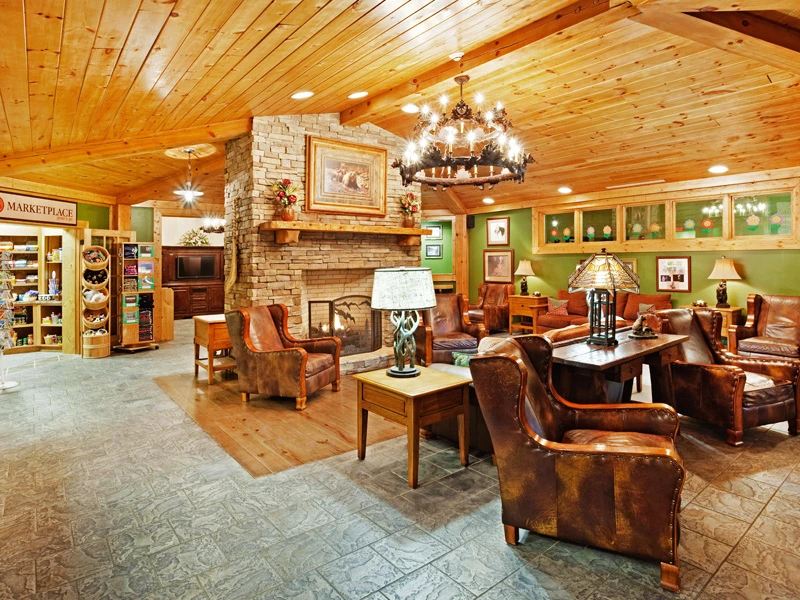 Rustic lobby area at a timeshare in gatlinburg with a cozy stone fireplace and leather armchairs.