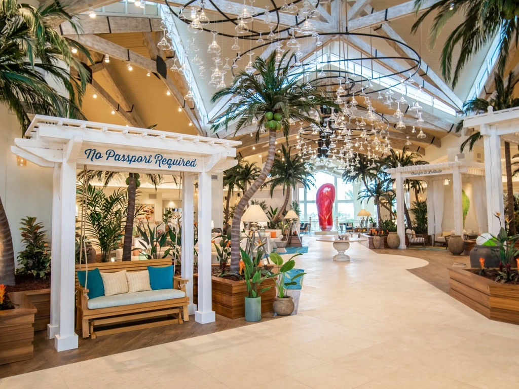 An expansive, beach-themed resort lobby featuring a giant red flip-flop sculpture and whimsical wine glass chandeliers. - why are timeshare resales so cheap?