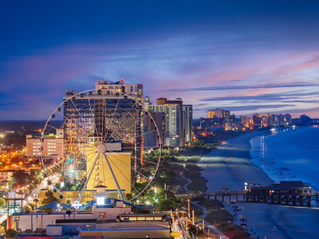 Illuminated SkyWheel and beachfront high-rises at twilight near a timeshare in Myrtle Beach.