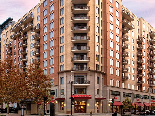 Exterior view of a multi-story brick resort building with balconies and a ground-floor pharmacy.