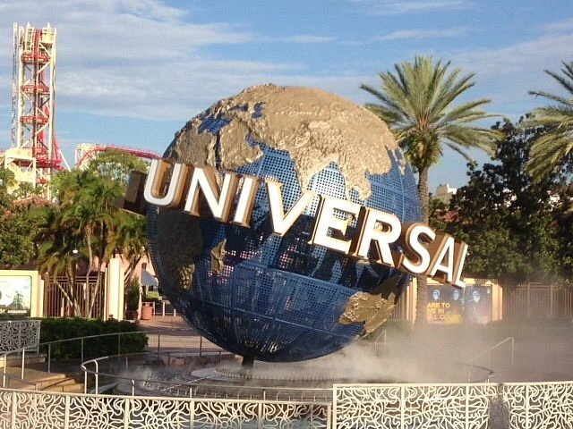 Large blue and gold globe fountain spinning over a misting pool, surrounded by tall palm trees.