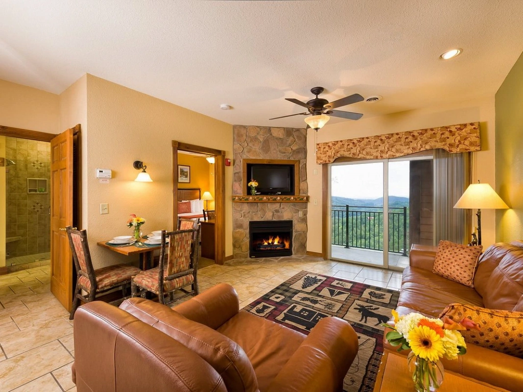 Relaxing living room with leather sofas, a stone fireplace, and balcony views at the Westgate Smoky Mountain Resort.