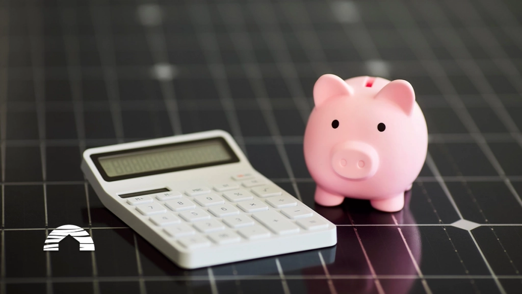 A pink piggy bank next to a white calculator on a black grid background, symbolizing financial savings.