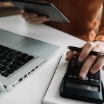 Person using a calculator, tablet, and laptop to figure out: do you pay closing costs on timeshare resales?