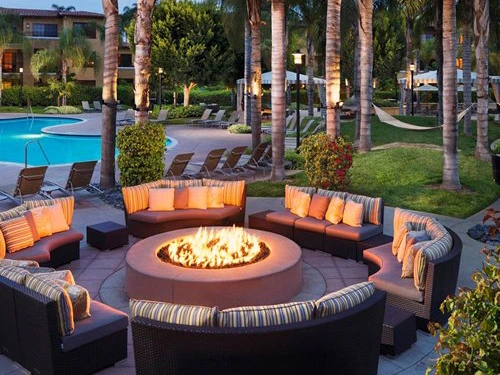 Evening summer vacation vibes at a large circular fire pit surrounded by modern outdoor sofas.