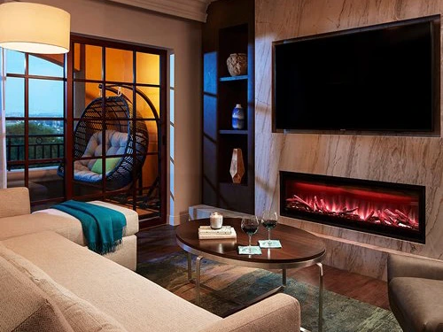Luxury resort living room with a sleek fireplace, wine glasses, and a summer vacation balcony view.