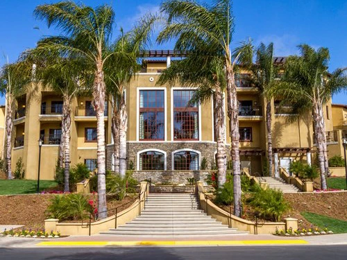 Grand Mediterranean-style entrance of MarBrisa resort with tall palm trees and stone stairs.