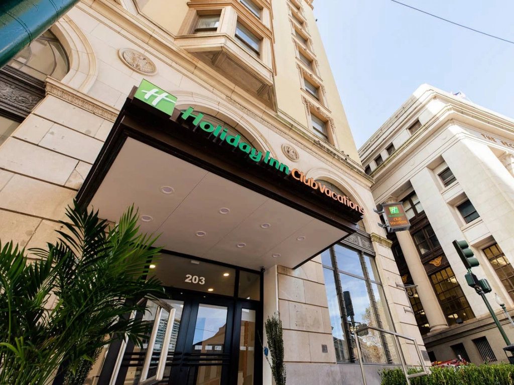 Low-angle view of the Holiday Inn Club Vacations canopy entrance on a historic multistory city building. - why are timeshare resales so cheap?