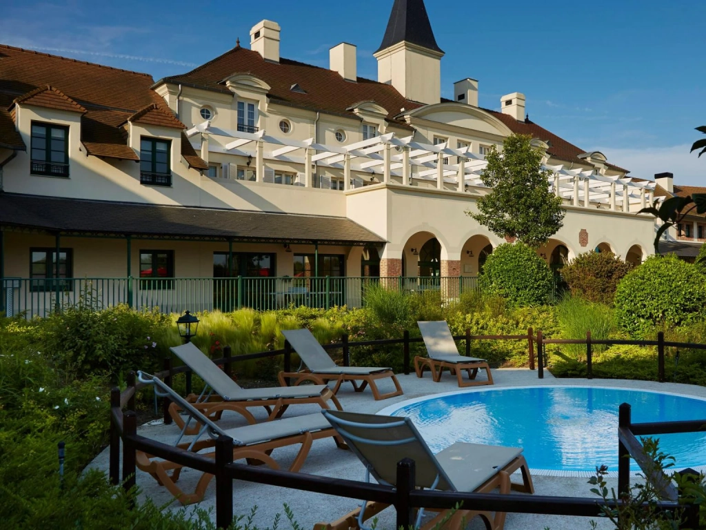 Lounge chairs around an outdoor hot tub outside the Marriott's Village d'Ile-de-France resort building.
