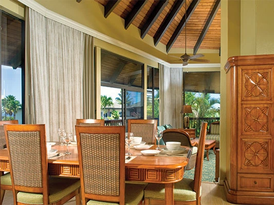 Formal dining room with wooden table, woven chairs, and vaulted ceilings at KaEoKai resort.