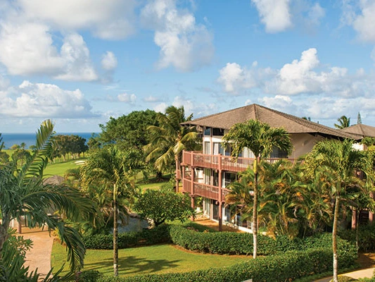 Lush green lawn and palm trees surrounding the multi-story KaEoKai resort buildings.