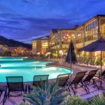 Lounge chairs surround a lit swimming pool at twilight at the Hyatt Vacation Club at The Welk timeshare in San Diego.