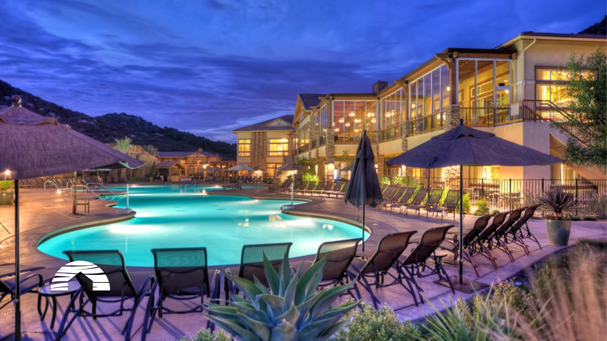 Lounge chairs surround a lit swimming pool at twilight at the Hyatt Vacation Club at The Welk timeshare in San Diego.