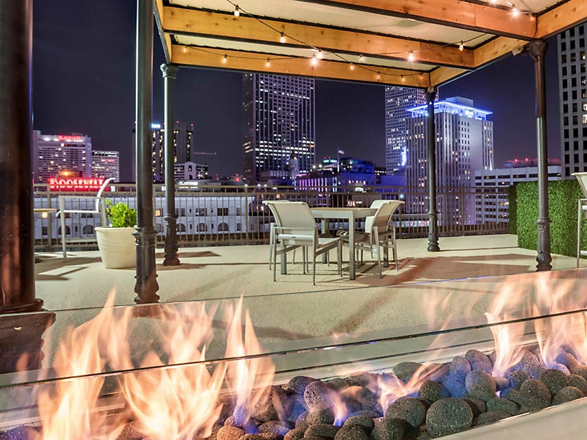 Rooftop patio at night with a glowing fire pit, seating, and city skyline views at The Marquee.