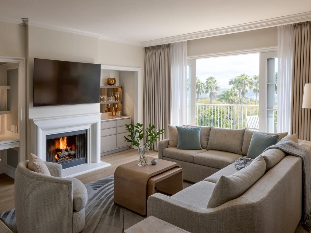 Sunlit living room with fireplace, neutral sofas, built-in bar, and palm tree balcony views at a San Diego timeshare.