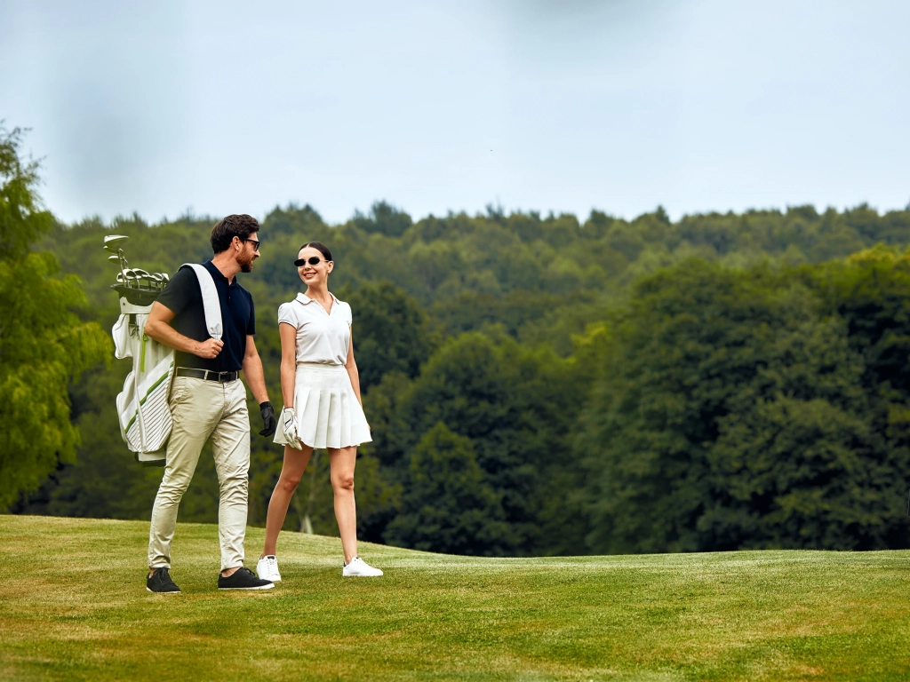 A couple walking along a green fairway during one of the best golf trips in the US.