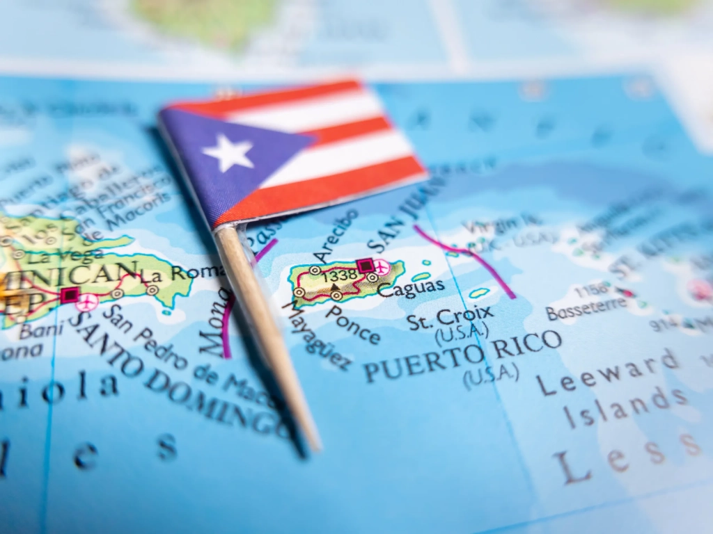Puerto Rico flag pin placed on a Caribbean map showing San Juan, Ponce, and neighboring Dominican Republic.