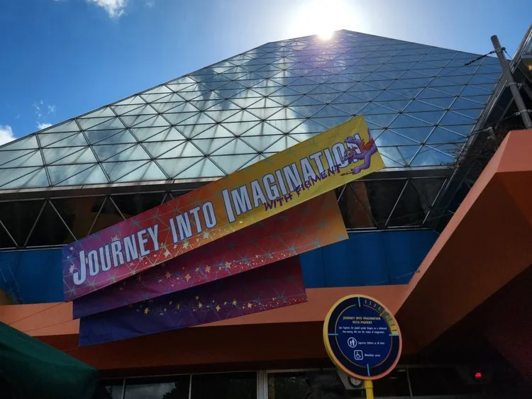 Figment attraction banner for one of the classic Epcot rides, displayed on the glass pyramid building.