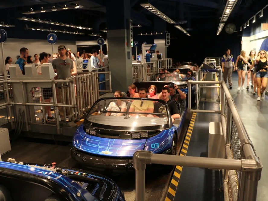 Guests board numbered vehicles for one of the classic Epcot rides inside a futuristic high-tech loading area.